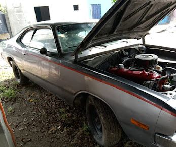 Silver classic two-door car with the hood up and the engine showing