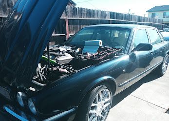 Dark green Jaguar sedan with the hood up
