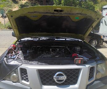 Nissan Xterra with the hood up and a jump pack connected